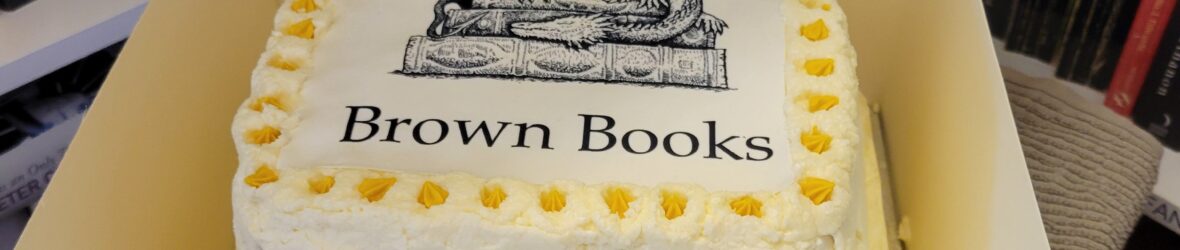 Two tiered birthday cake with Brown Books logo on the top and Happy Birthday banner
