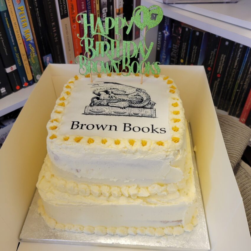 Two tiered birthday cake with Brown Books logo on the top and Happy Birthday banner